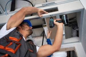  Technicians installing a garage door mechanism using a drill, showcasing professional expertise